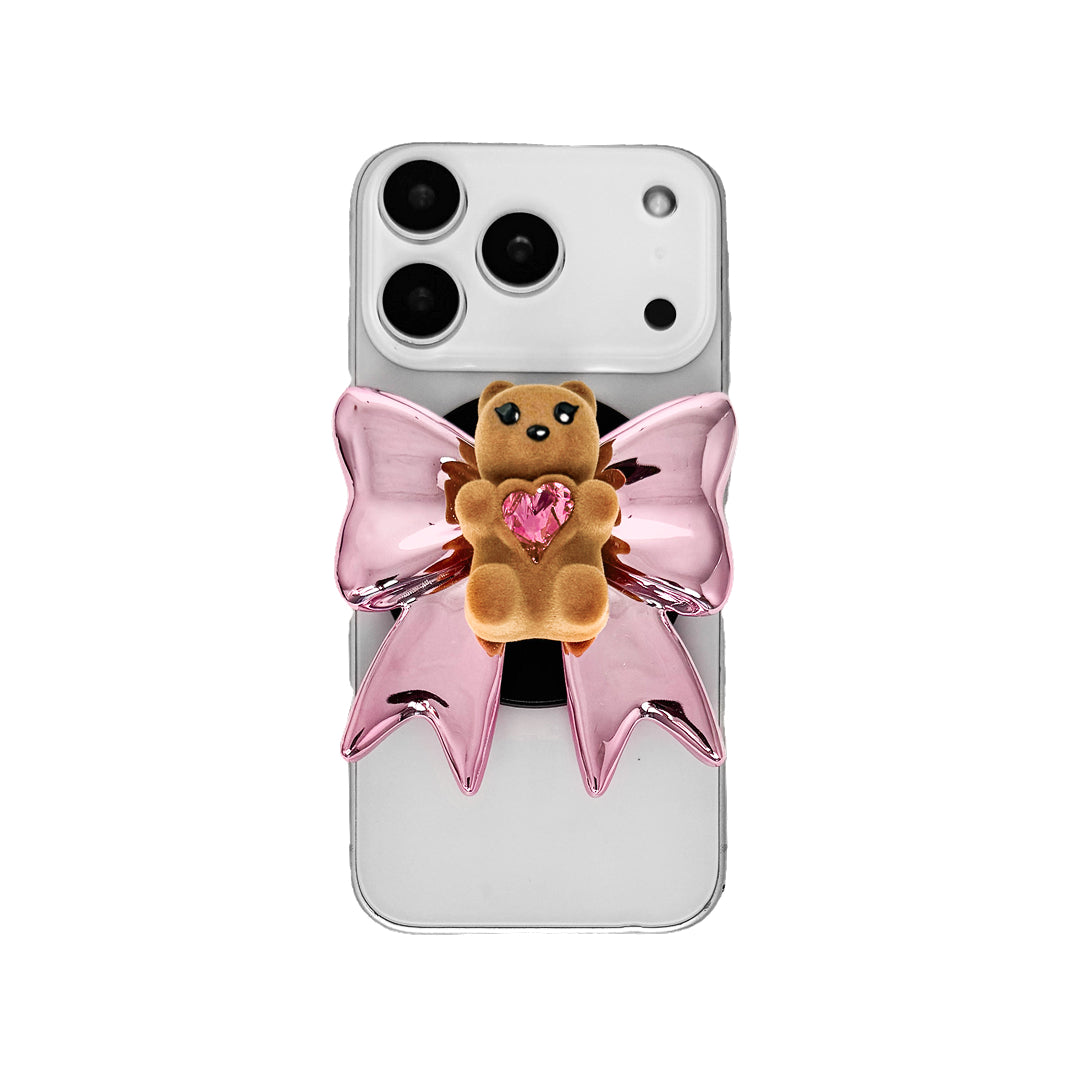 Bow Magic Bear Phone Grip featuring a glossy silver bow with a black gummy bear at the center, holding a sparkling heart-shaped crystal.