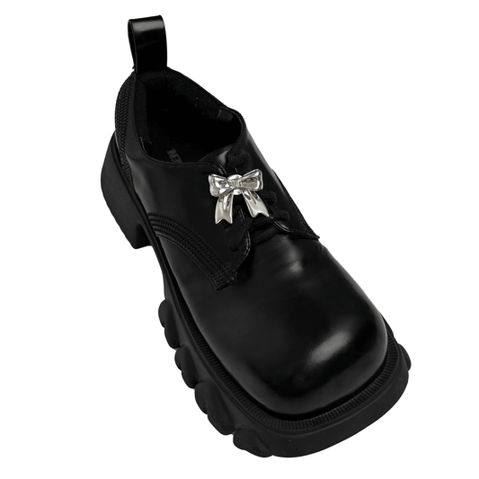 A silver metallic bow knot shoelace charm with a polished finish, adding a stylish and elegant accent to sneakers.