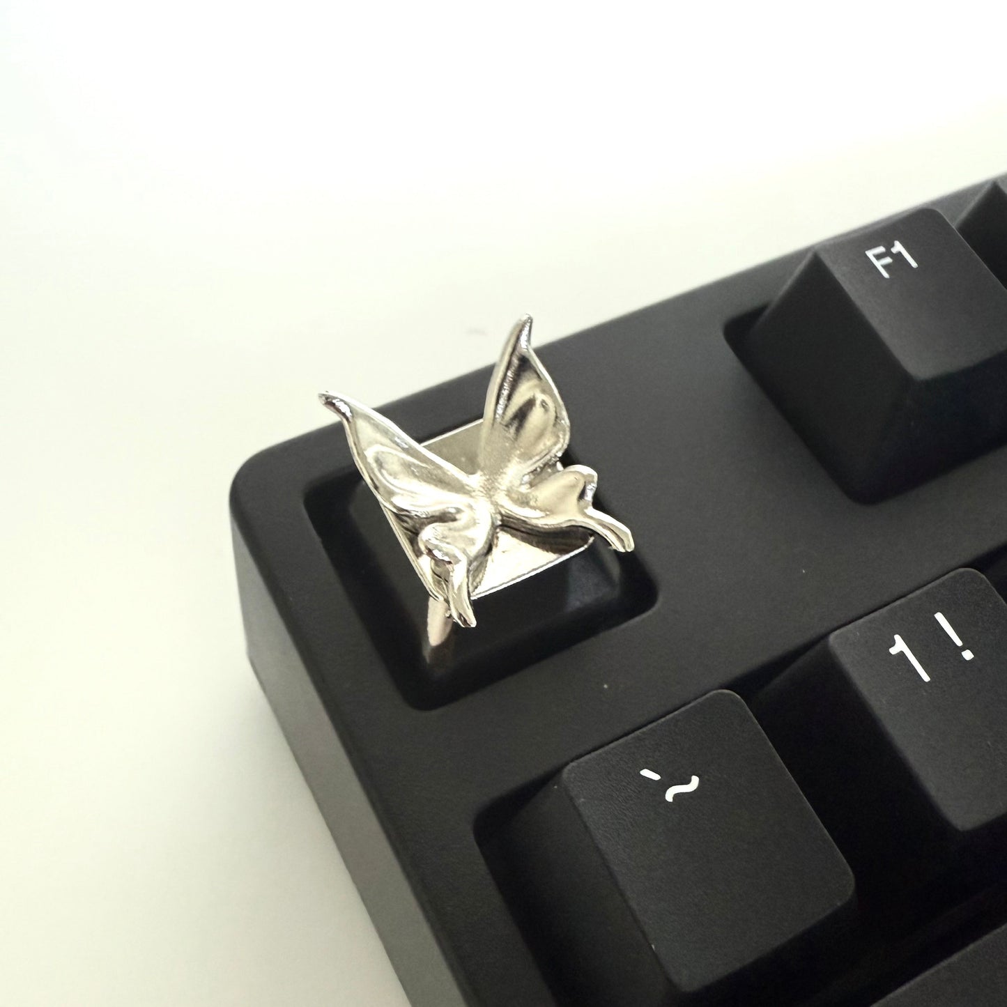 Close-up of a black keyboard with a decorative keycap featuring a silver insect design.