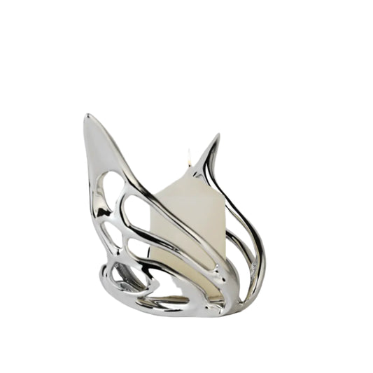 Futuristic chrome butterfly candle holder with wing-inspired curved frame – sculptural metallic design encasing a pillar candle