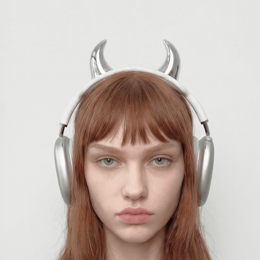 Person wearing silver headphones with devil horns on a light gray background