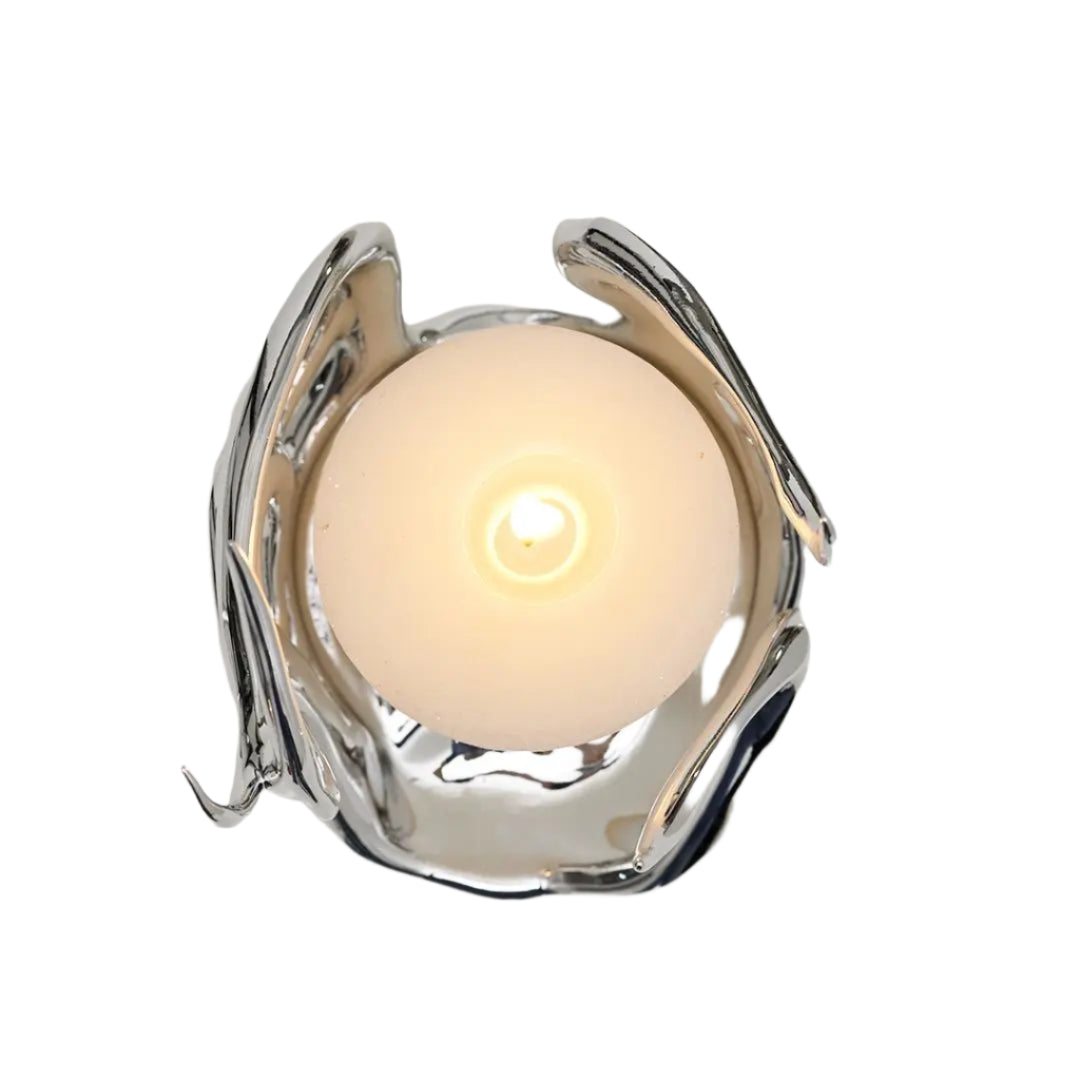 Sculptural silver candleholder with flowing flame-like curves embracing a short ivory candle — modern centerpiece for elegant decor