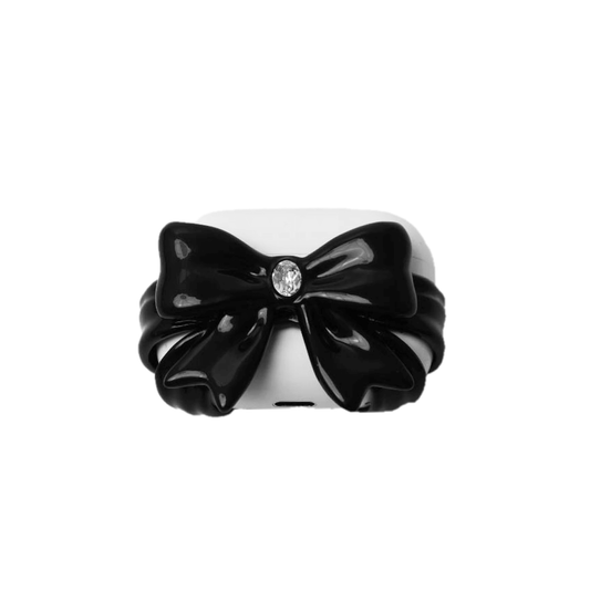 Black and white AirPods case covers featuring a sculpted 3D bow adorned with white gemstones; hard protective SLA shell designed for AirPods 4, AirPods Pro 2, and AirPods Pro 3.