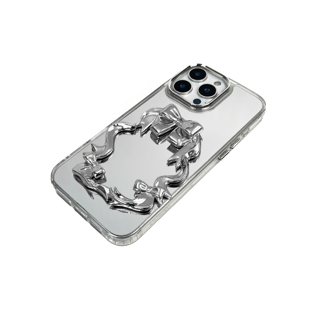 Mirror phone case with sculpted pink, silver, black and white bows and ribbon frame design, creating a romantic, soft-glam look.