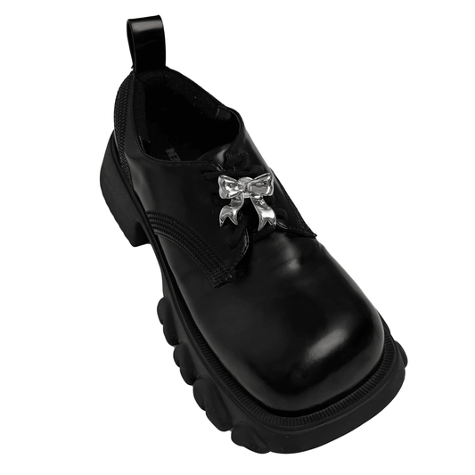 A silver metallic silken ribbon shoelace charm with flowing curves, giving a graceful and delicate accent to sneakers.