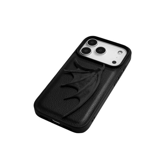 A high-fashion iPhone case featuring a large, 3D-printed single demon wing with a natural matte black finish. The design is presented in two styles: an asymmetric wing on a Clear Transparent base, and the same sculptural wing on a Black Leather textured base, showcasing a moody and avant-garde aesthetic.