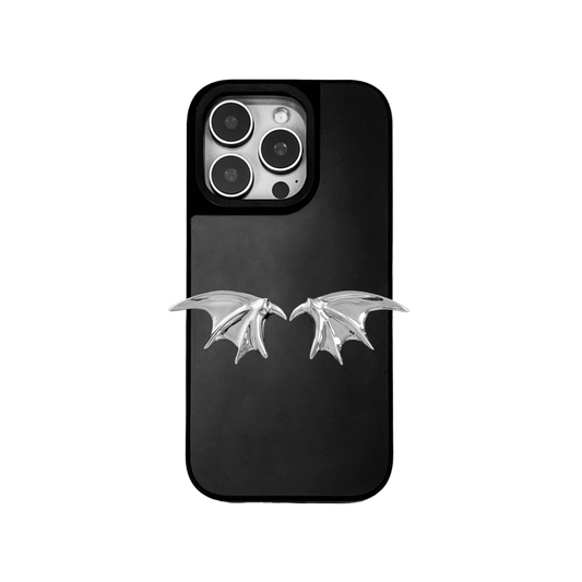 A high-fashion iPhone case featuring a pair of miniature 3D sculpted demon wings in a reflective silver chrome finish. The product is shown in three variations: a Reflective Silver base, a Sleek Black base, and a Clear Transparent base, all accented by the metallic silver wing ornament.
