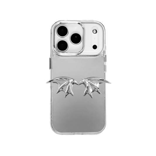 A high-fashion iPhone case featuring a pair of miniature 3D sculpted demon wings in a reflective silver chrome finish. The product is shown in three variations: a Reflective Silver base, a Sleek Black base, and a Clear Transparent base, all accented by the metallic silver wing ornament.