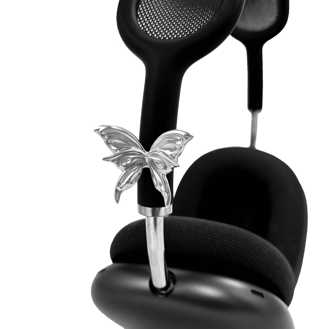 Chrome butterfly-shaped decorative accessory attached to AirPods Max.