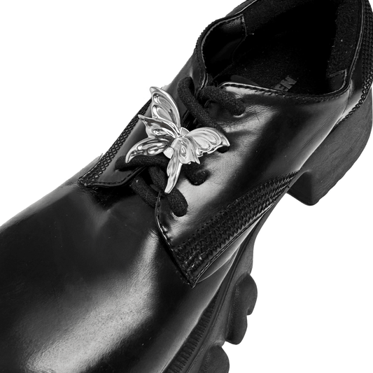 A silver metallic 3D butterfly shoelace charm with raised wings, creating a sculptural and dynamic look on sneakers.