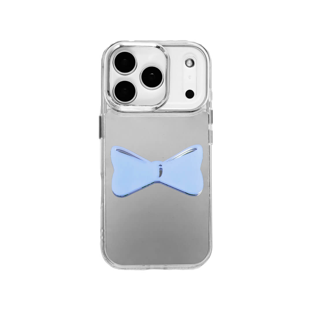 A modern iPhone case featuring a 3D acrylic bow/ribbon ornament. Available in Sakura Pink and Azure Blue acrylic finishes. The case is shown on both a Reflective Silver metallic base and a Clear Transparent base, showcasing a minimalist yet playful fashion aesthetic.