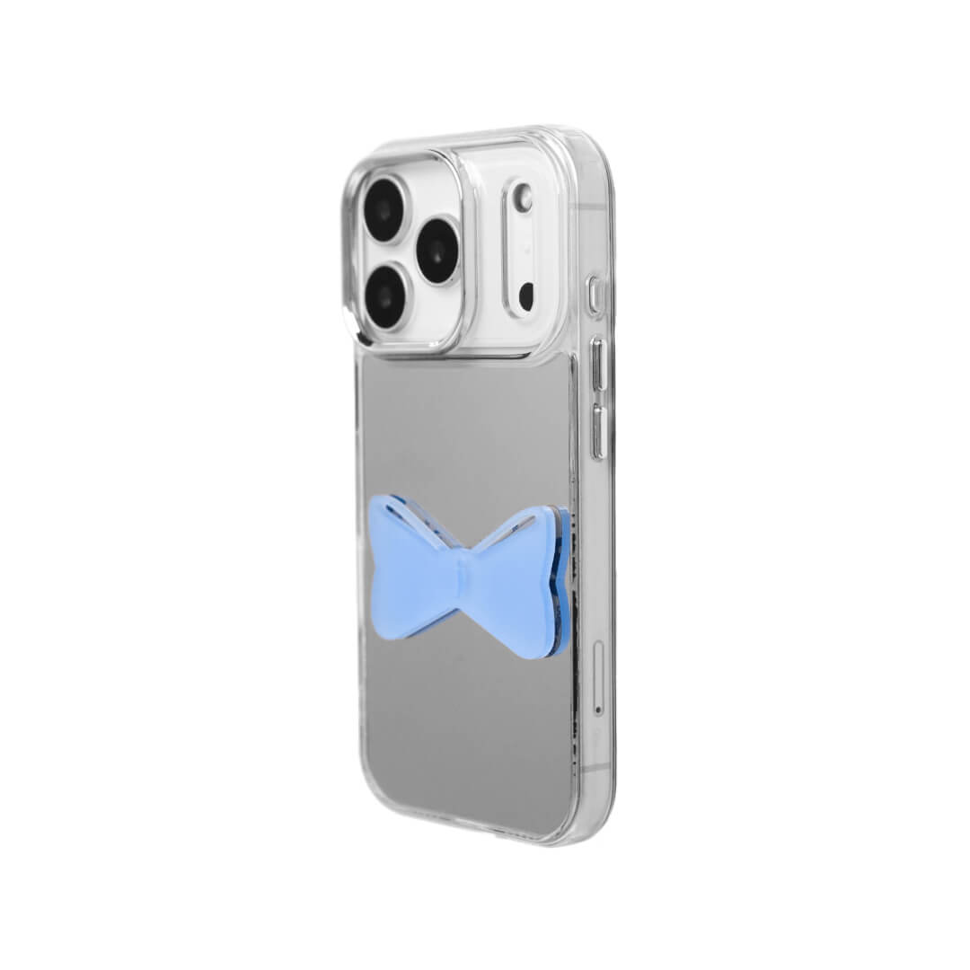A modern iPhone case featuring a 3D acrylic bow/ribbon ornament. Available in Sakura Pink and Azure Blue acrylic finishes. The case is shown on both a Reflective Silver metallic base and a Clear Transparent base, showcasing a minimalist yet playful fashion aesthetic.