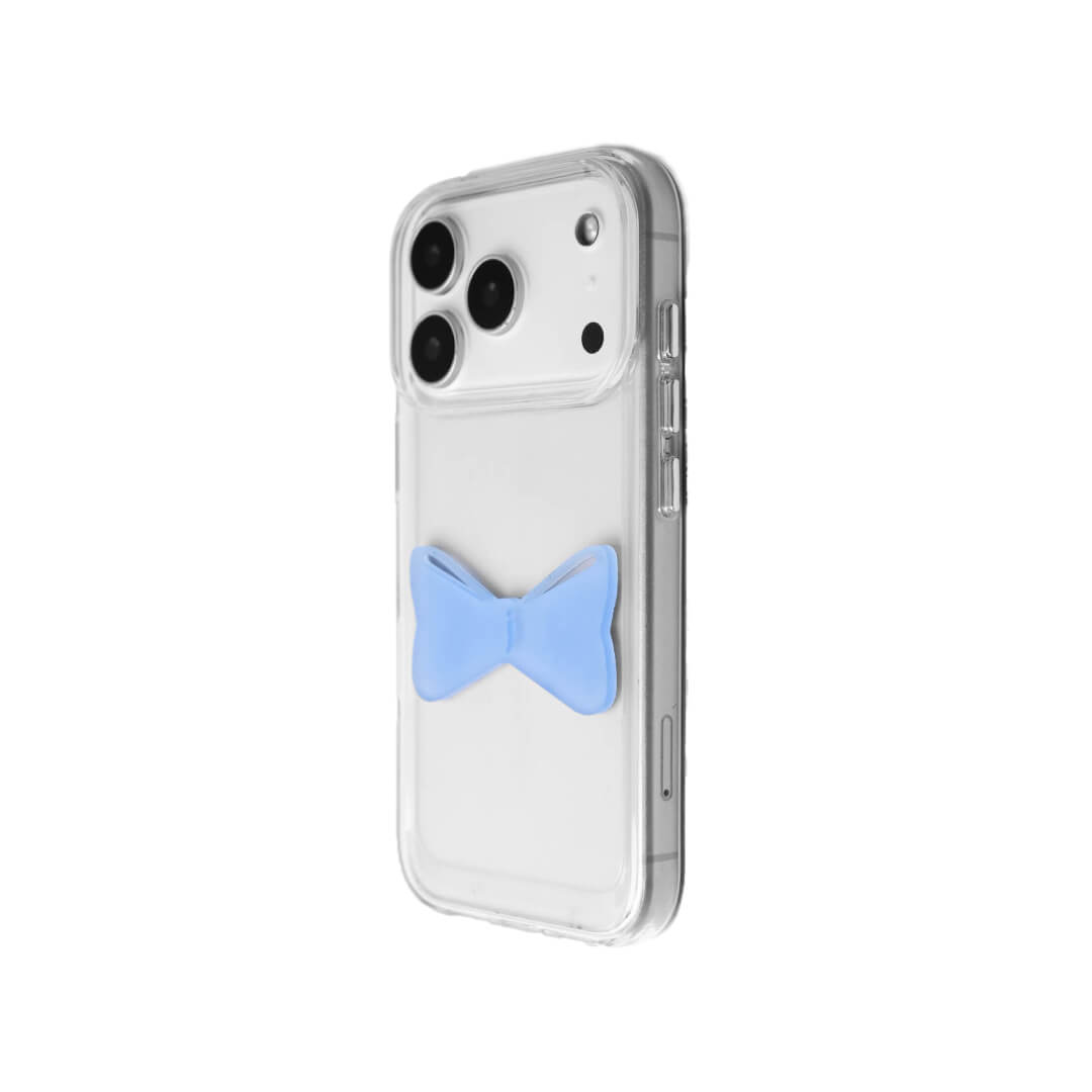 A modern iPhone case featuring a 3D acrylic bow/ribbon ornament. Available in Sakura Pink and Azure Blue acrylic finishes. The case is shown on both a Reflective Silver metallic base and a Clear Transparent base, showcasing a minimalist yet playful fashion aesthetic.