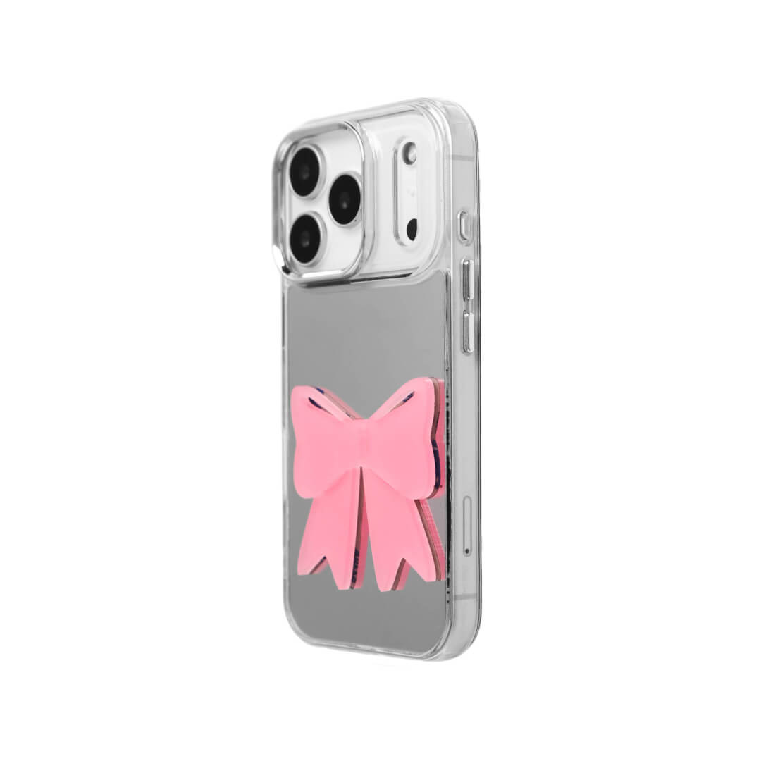 A modern iPhone case featuring a 3D acrylic ribbon ornament with long, flowing tails. Available in Sakura Pink and Azure Blue finishes. The case is shown on both a Reflective Silver metallic base and a Clear Transparent base, showcasing a minimalist yet playful fashion aesthetic.