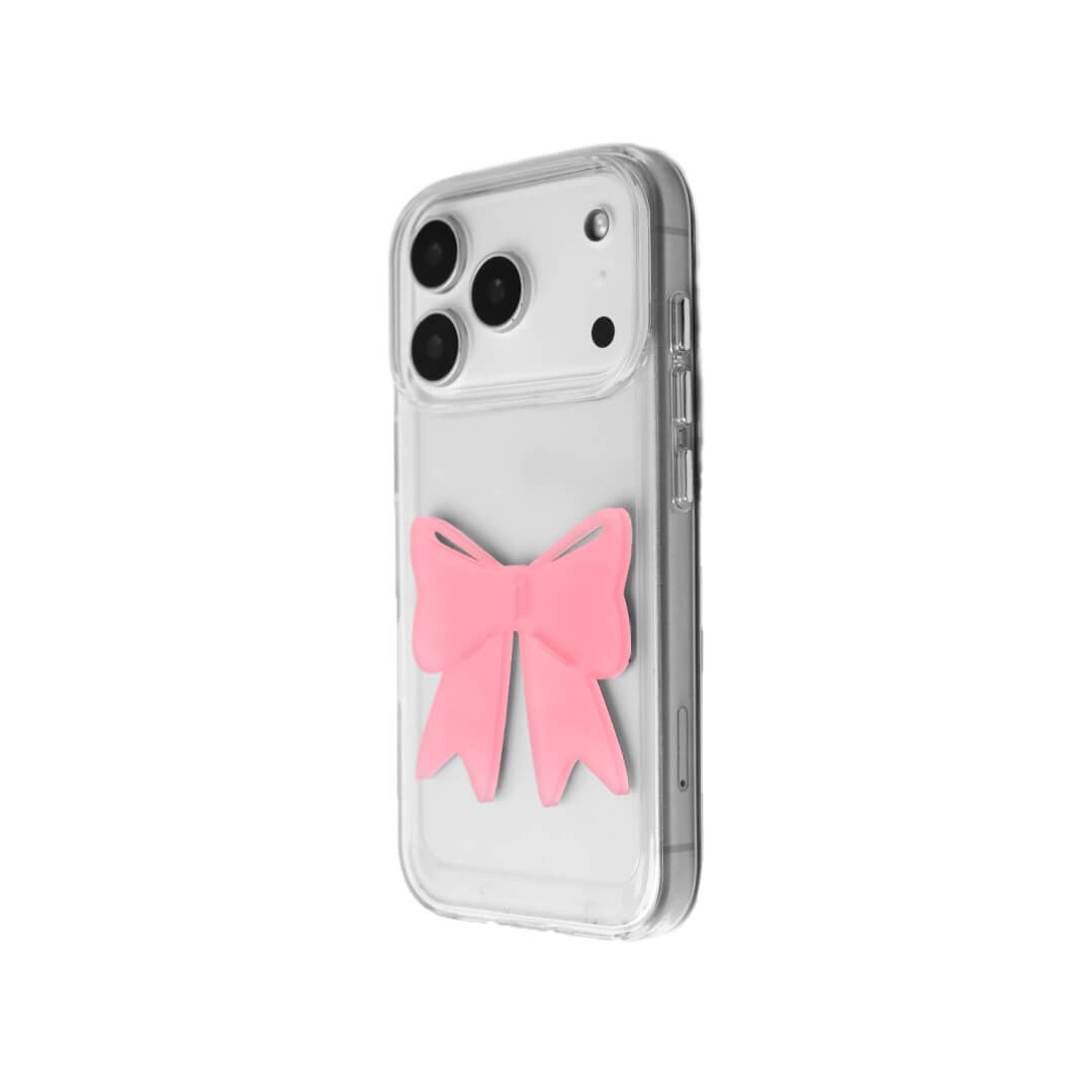 A modern iPhone case featuring a 3D acrylic ribbon ornament with long, flowing tails. Available in Sakura Pink and Azure Blue finishes. The case is shown on both a Reflective Silver metallic base and a Clear Transparent base, showcasing a minimalist yet playful fashion aesthetic.