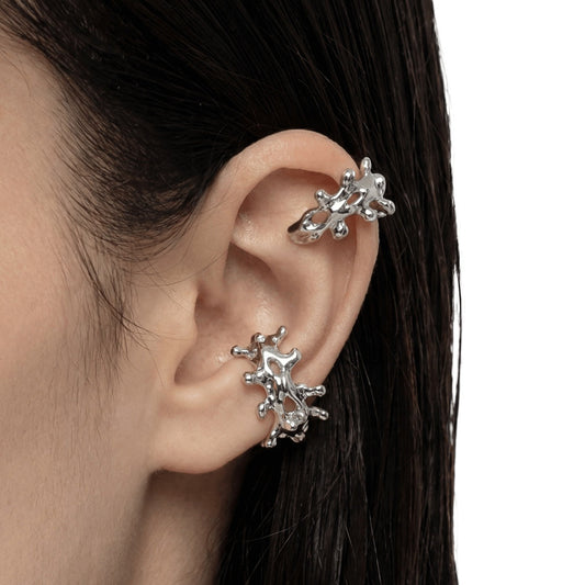 Silver ear cuff and earrings worn by a person with dark hair on a white background