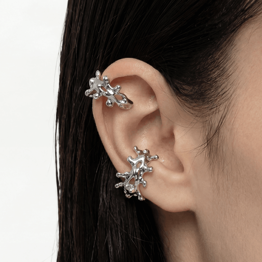 Silver ear cuff and earrings worn by a person with dark hair on a white background