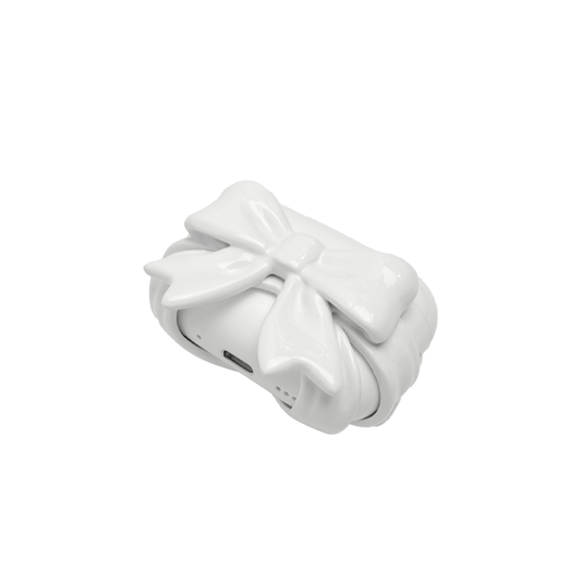 A pair of protective covers for Apple AirPods (or AirPods Pro) charging case. Each cover is white and features a large, 3D sculpted bow charm centered on the front. One bow is glossy black and the other is pure white.