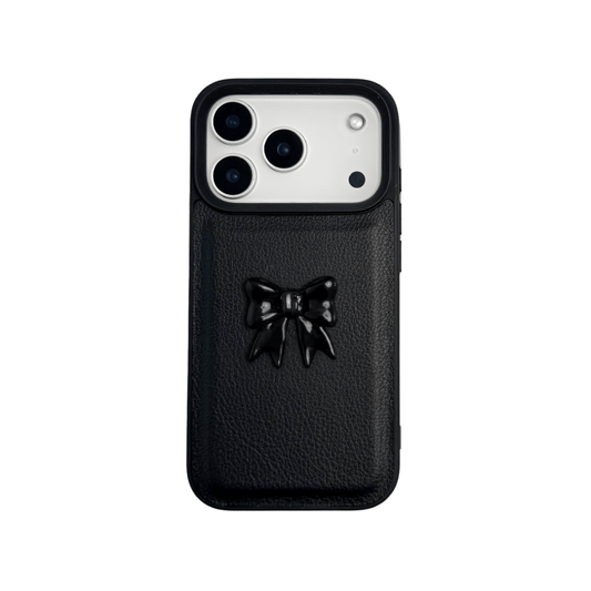 A pair of luxury iPhone cases featuring a textured, high-quality leather finish. Each case has a large, centered, 3D sculpted bow on the back. The top case is Off-White leather with a matching bow, and the bottom case is Black leather with a matching black bow.