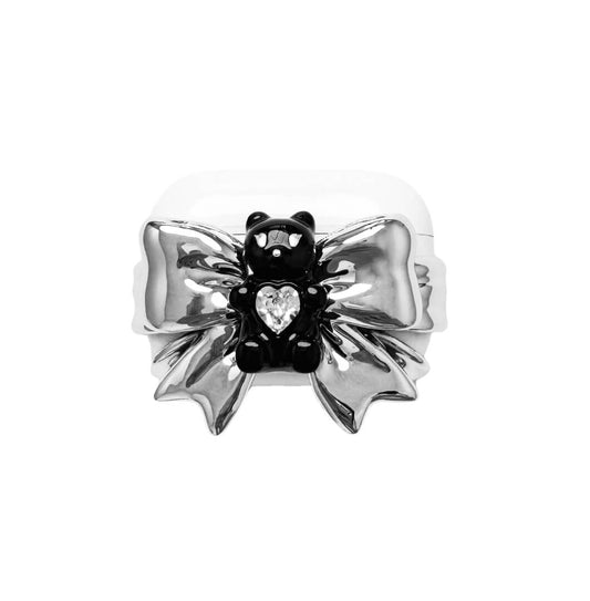 Bow Magic Bear AirPods Cover featuring a glossy black gummy bear holding a crystal heart, centered on metallic silver bow-shaped detailing.