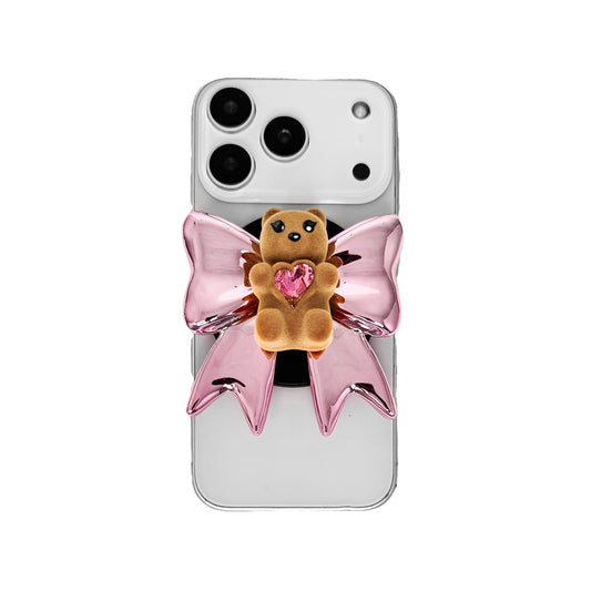 Bow Magic Bear Phone Grip featuring a glossy silver bow with a black gummy bear at the center, holding a sparkling heart-shaped crystal.