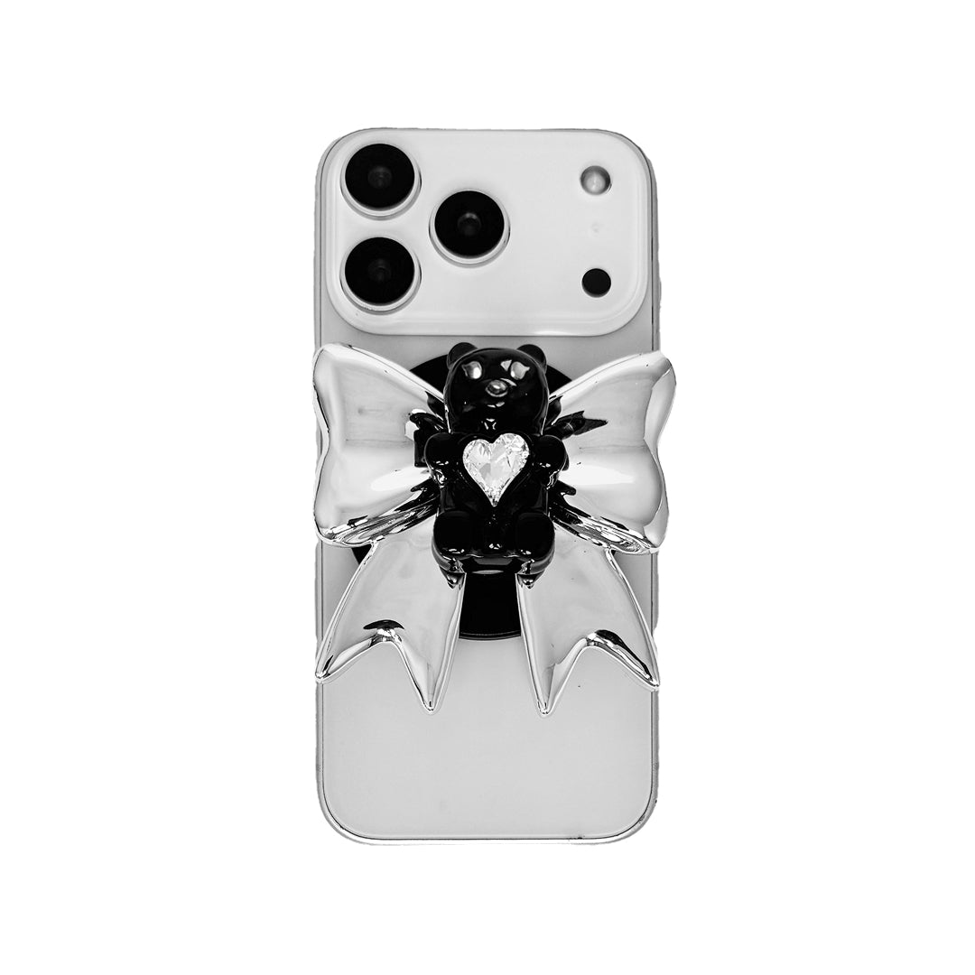 Bow Magic Bear Phone Grip featuring a glossy silver bow with a black gummy bear at the center, holding a sparkling heart-shaped crystal.