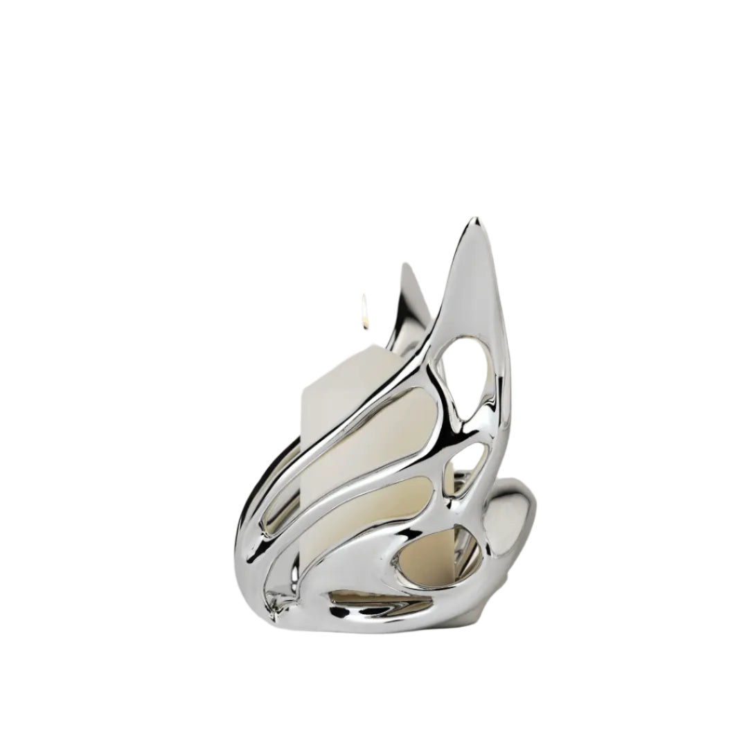 Futuristic chrome butterfly candle holder with wing-inspired curved frame – sculptural metallic design encasing a pillar candle