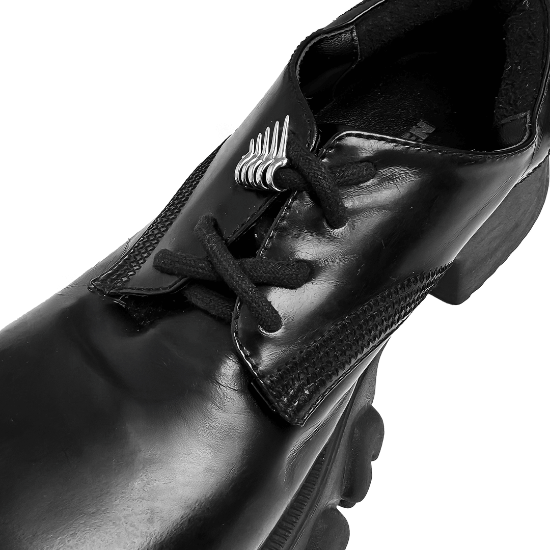 A metallic shoelace charm featuring claw-like spikes with looped rings, designed to slide onto shoelaces for a bold and edgy look.