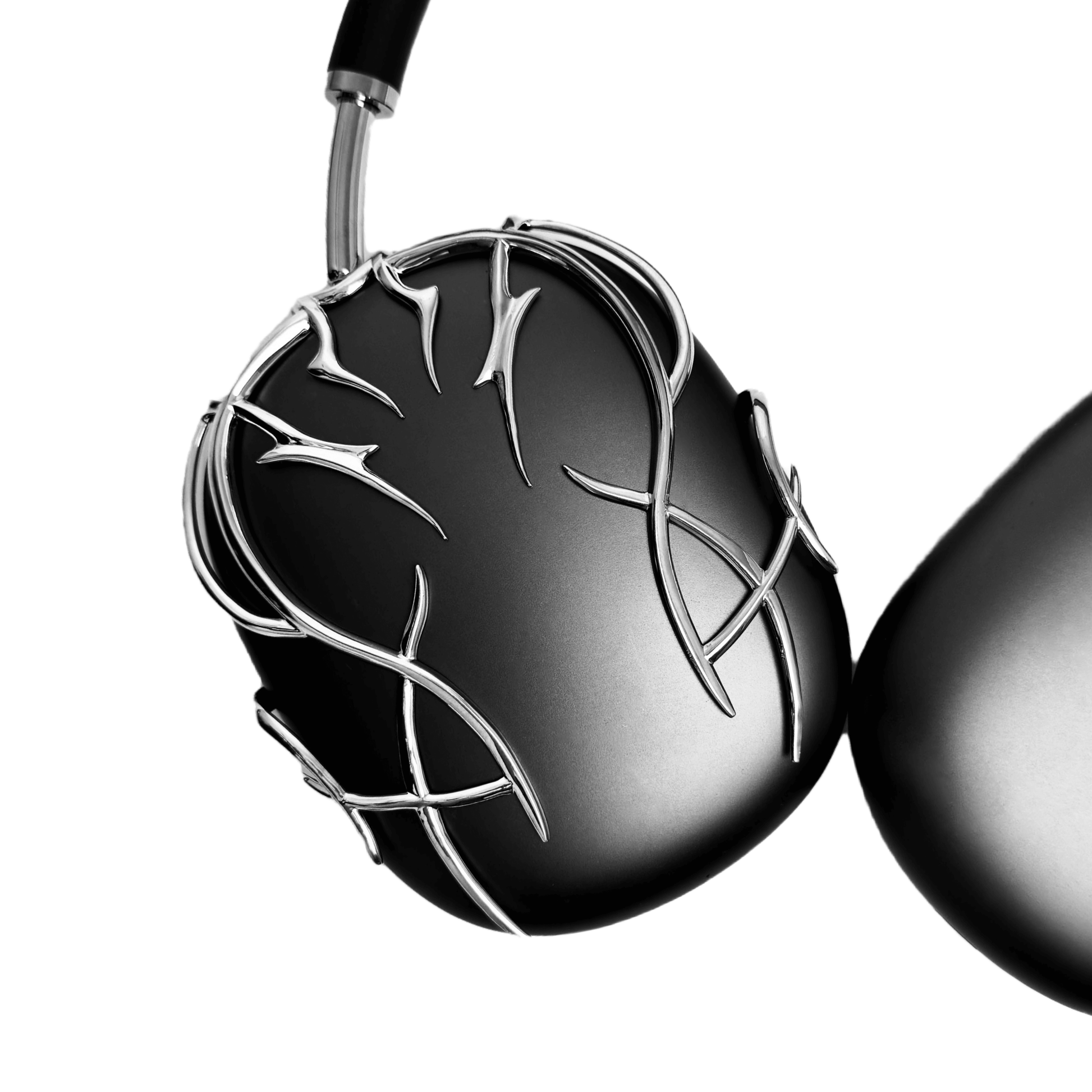 The XTENDED iDENTiTY "Cyber-Dreams" AirPods Max Cover from the Cyber Dream series. The black earcups are protected by a metallic, interwoven exoskeleton structure. The design showcases fluid, multi-layered lines forming a protective, woven mesh. Available finishes include Shadow Black, Liquid Silver, and Molten Gold.