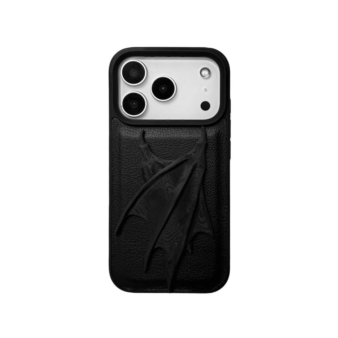 A high-concept iPhone case featuring a large, 3D-printed double demon wing ornament with a natural matte black finish. The wings are shown in two variations: one mounted on a Clear Transparent base, and another on a premium Black Litchi Leather textured base, highlighting the intricate, organic details of the sculptural wings.