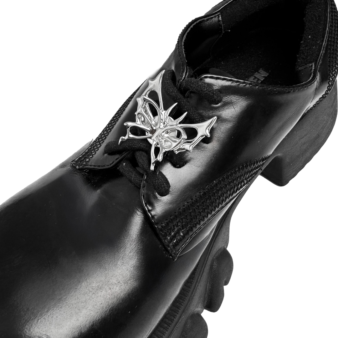 A silver metallic filigree butterfly shoelace charm with intricate openwork details, adding elegance and a luxurious accent to sneakers.