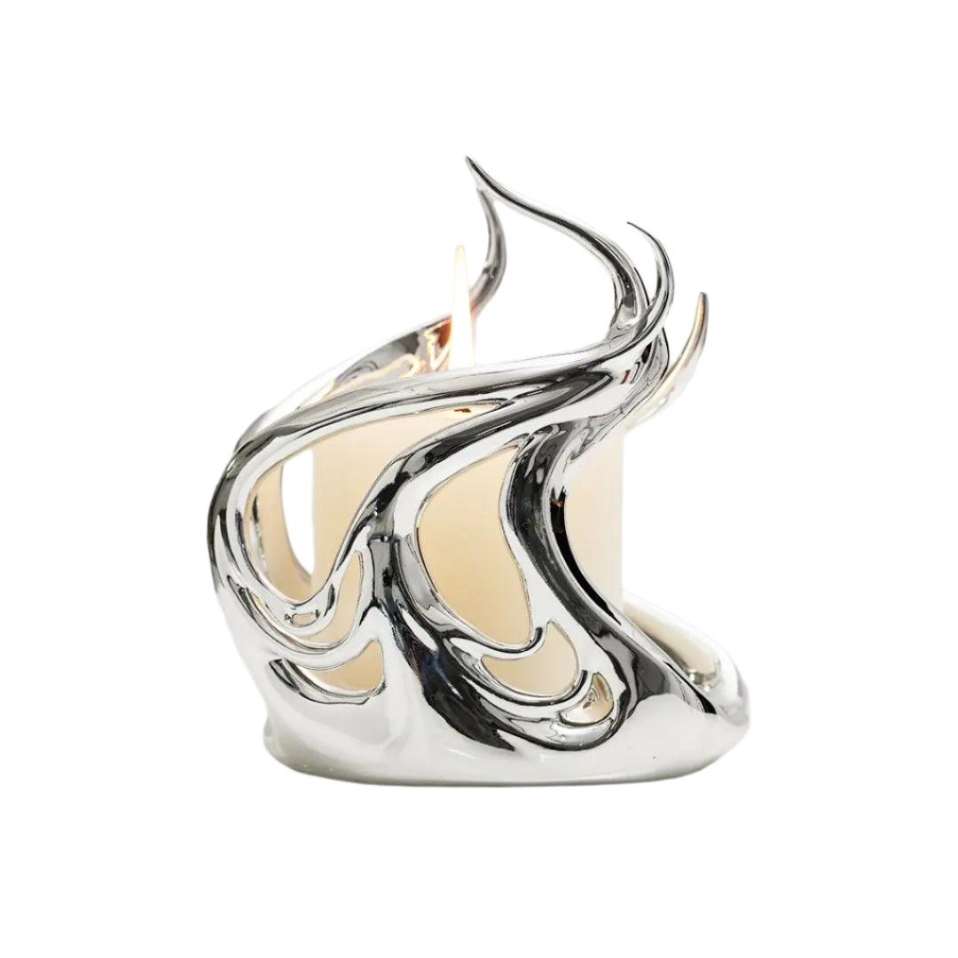 Sculptural silver candleholder with flowing flame-like curves embracing a short ivory candle — modern centerpiece for elegant decor