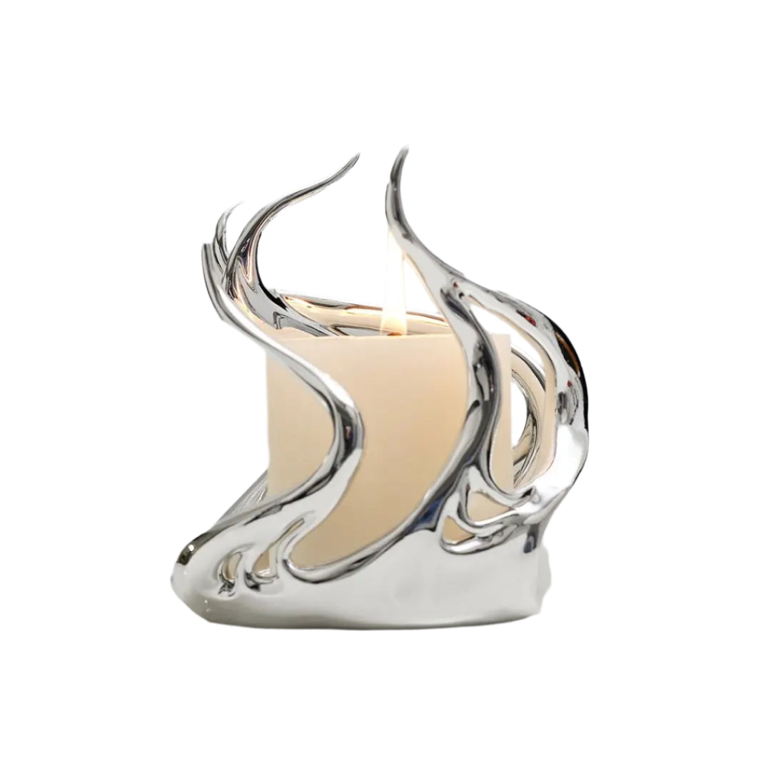 Sculptural silver candleholder with flowing flame-like curves embracing a short ivory candle — modern centerpiece for elegant decor