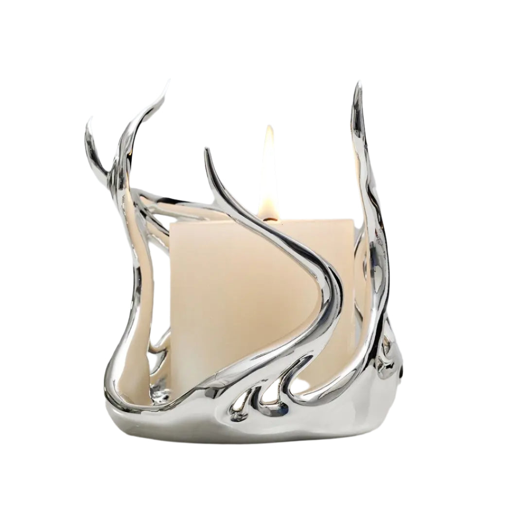 Sculptural silver candleholder with flowing flame-like curves embracing a short ivory candle — modern centerpiece for elegant decor