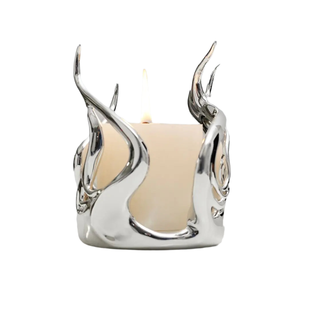 Sculptural silver candleholder with flowing flame-like curves embracing a short ivory candle — modern centerpiece for elegant decor