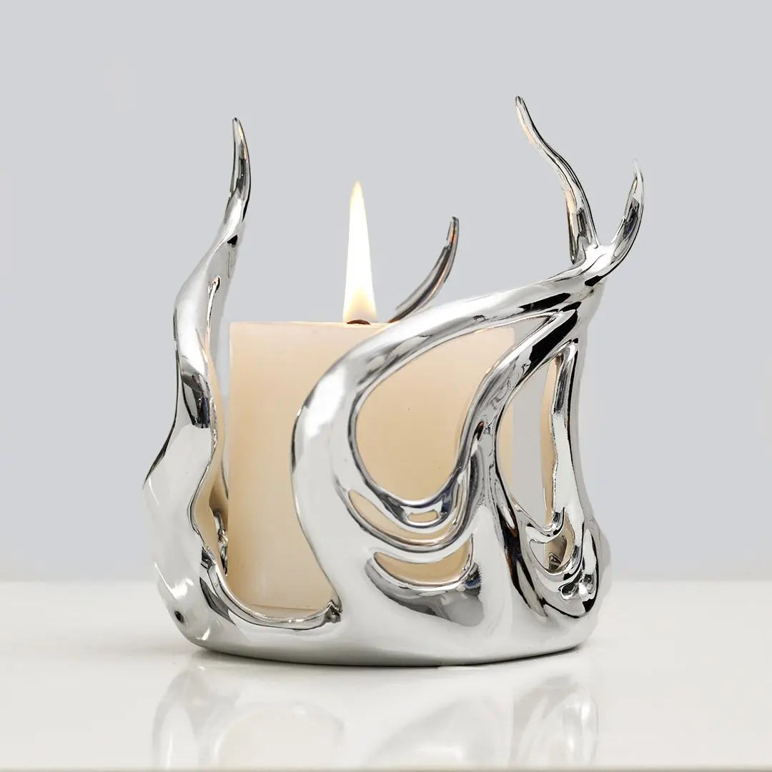 Sculptural silver candleholder with flowing flame-like curves embracing a short ivory candle — modern centerpiece for elegant decor