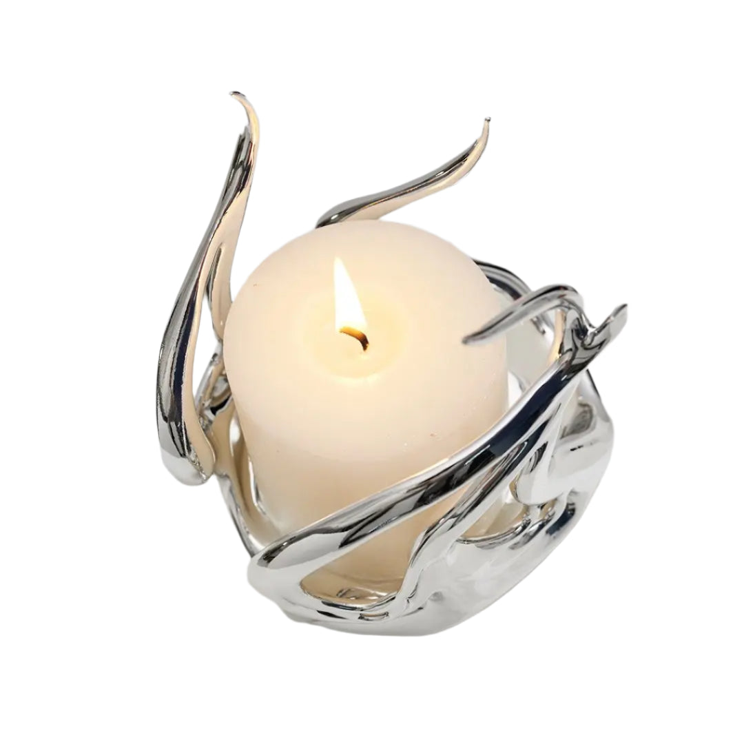 Sculptural silver candleholder with flowing flame-like curves embracing a short ivory candle — modern centerpiece for elegant decor