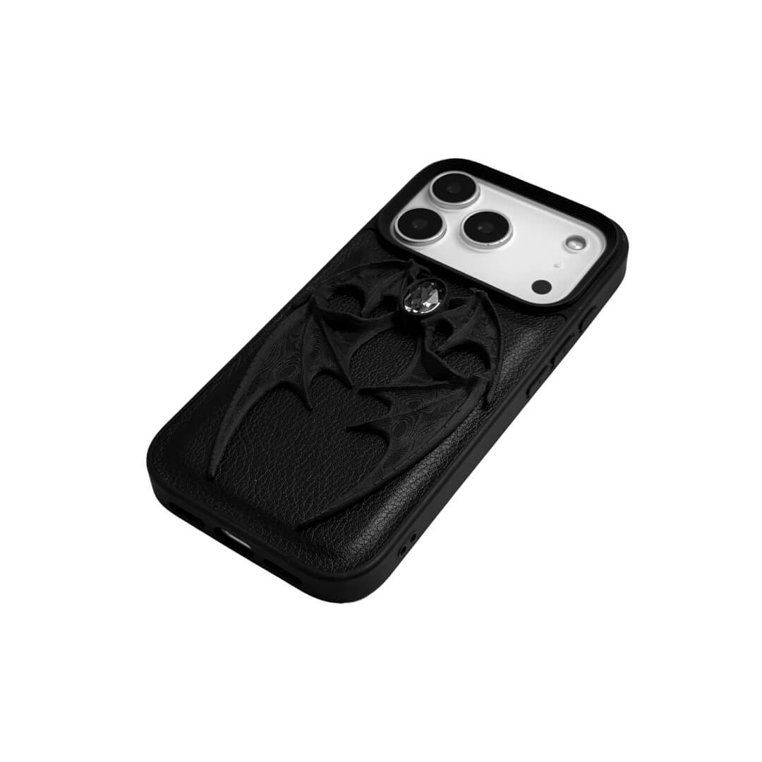 A high-fashion iPhone case featuring a pair of 3D-printed demon wings curving around a central sparkling gem, all in a natural matte black finish. Available in two variations: a minimalist Clear Transparent base and a luxurious Black Leather textured base, showcasing the intricate and edgy sculptural design.