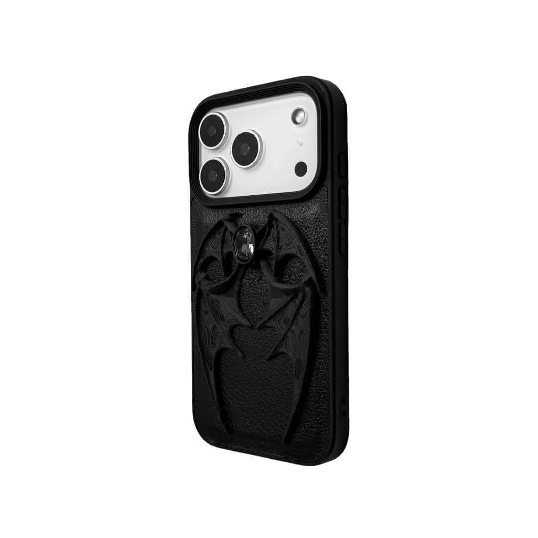 A high-fashion iPhone case featuring a pair of 3D-printed demon wings curving around a central sparkling gem, all in a natural matte black finish. Available in two variations: a minimalist Clear Transparent base and a luxurious Black Leather textured base, showcasing the intricate and edgy sculptural design.