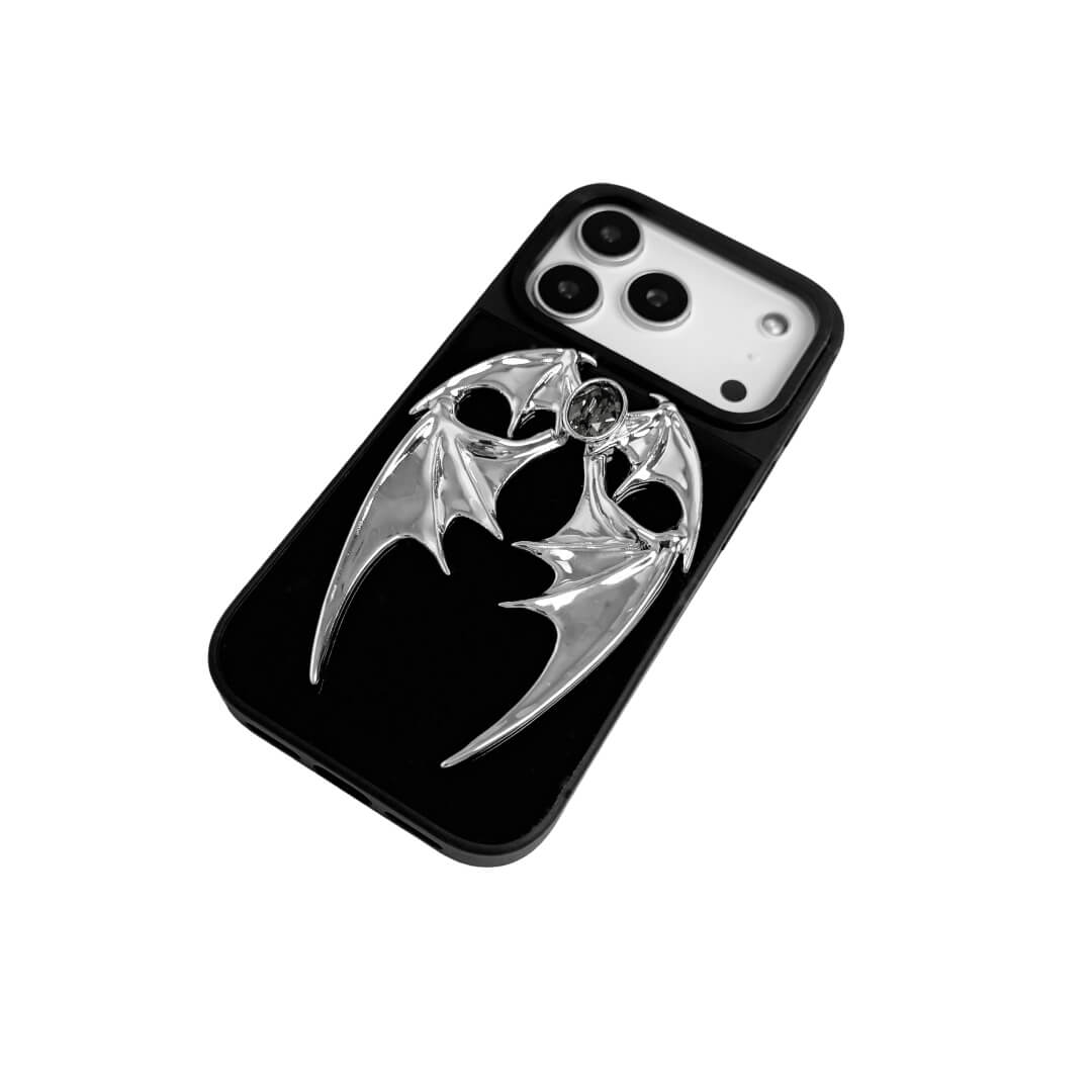 The Gem Demon Wings iPhone Case featuring 3D sculpted silver metallic bat-style wings with a central rhinestone. Shown with both White and Black gem options, available on Silver, Transparent, and Black case bases.