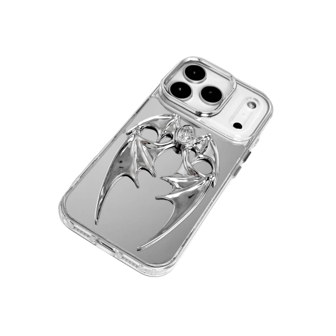 The Gem Demon Wings iPhone Case featuring 3D sculpted silver metallic bat-style wings with a central rhinestone. Shown with both White and Black gem options, available on Silver, Transparent, and Black case bases.