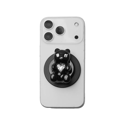 The Gem Gummy Bear phone grip collection featuring the sculpted 3D bear holding a sparkling central heart gem, shown in both the reflective Silver Chrome and glossy Black finish options.