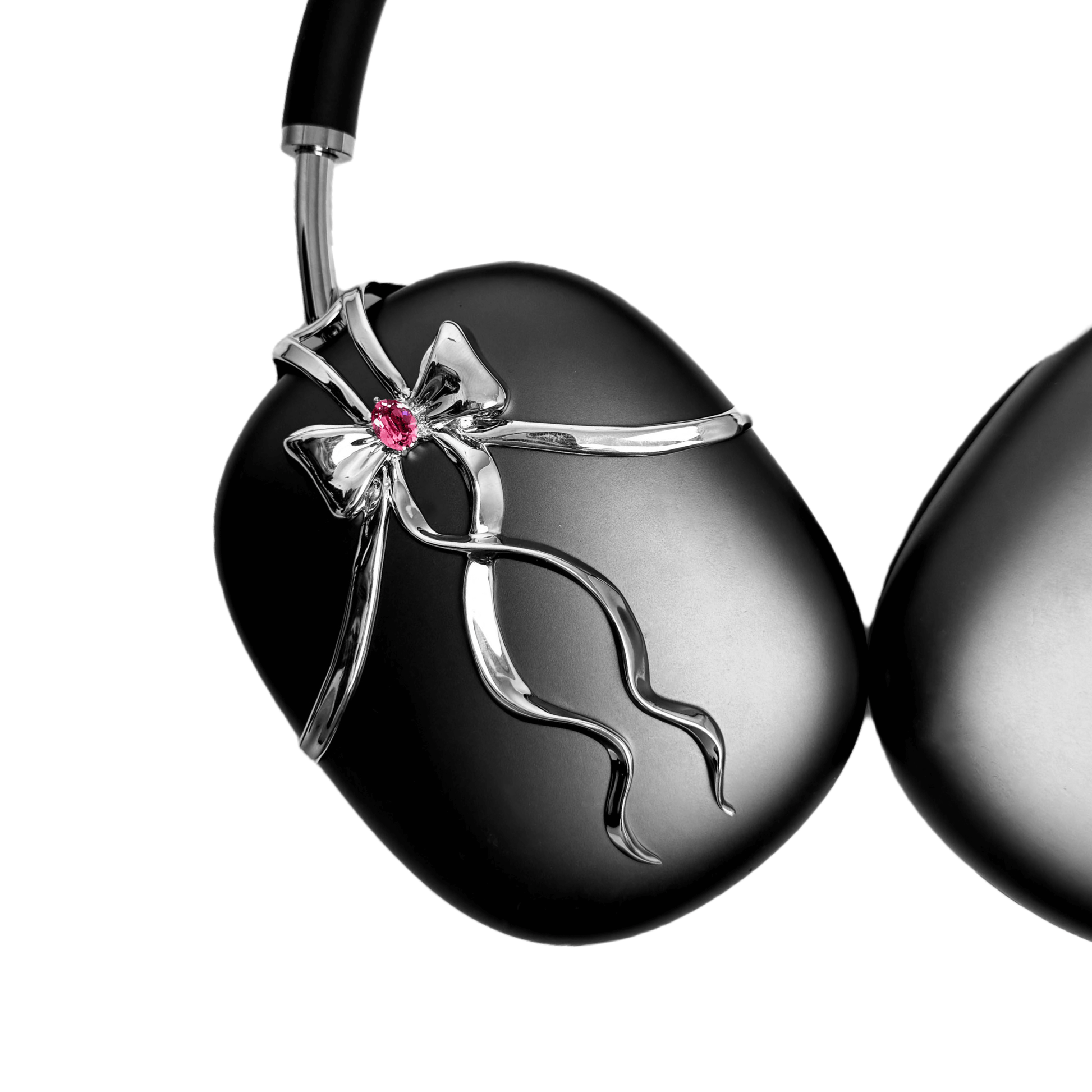 AirPods Max cover with sculpted metallic black/silver shells, adorned with a flowing 3D ribbon design and highlighted by a shimmering Pink Gem (Swarovski Crystal), creating a luxurious, statement look.