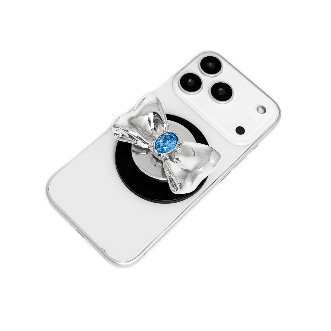 Gem Bow Phone Grip S available in silver, pink, black, and white bows, each featuring Swarovski crystal options: silver with pink, purple, white, blue, or black gems; pink with pink gem; black and white with black, white, or pink gems.