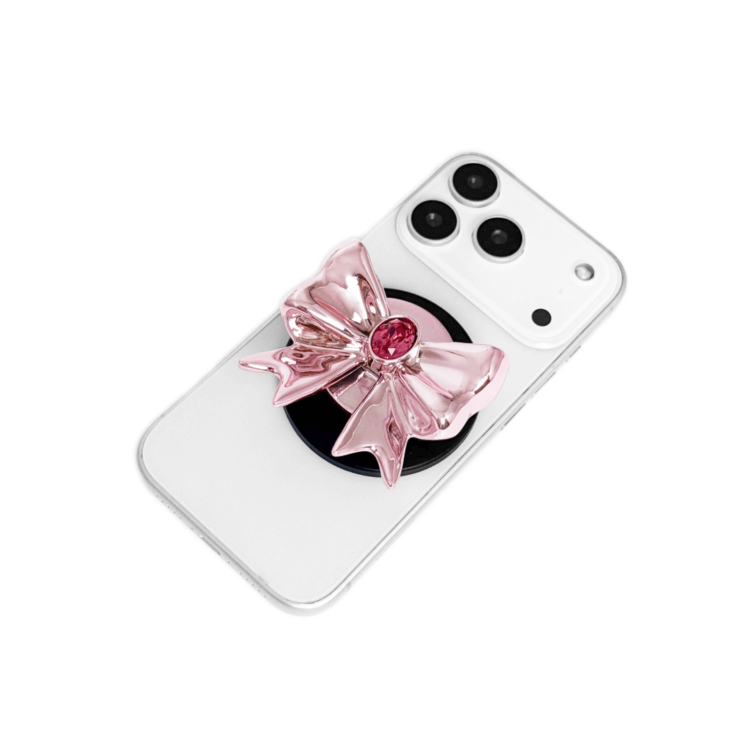 Gem Ribbon Phone Grip S available in silver, pink, black, and white ribbon designs, each featuring Swarovski crystal options: silver with pink, purple, white, blue, or black gems; pink with pink gem; black and white with black, white, or pink gems.
