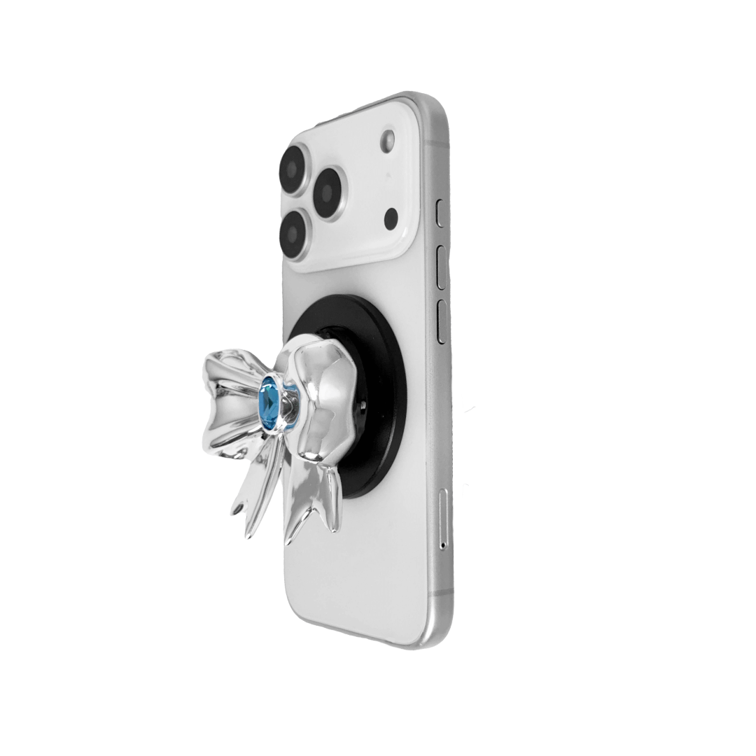 Gem Ribbon Phone Grip S available in silver, pink, black, and white ribbon designs, each featuring Swarovski crystal options: silver with pink, purple, white, blue, or black gems; pink with pink gem; black and white with black, white, or pink gems.