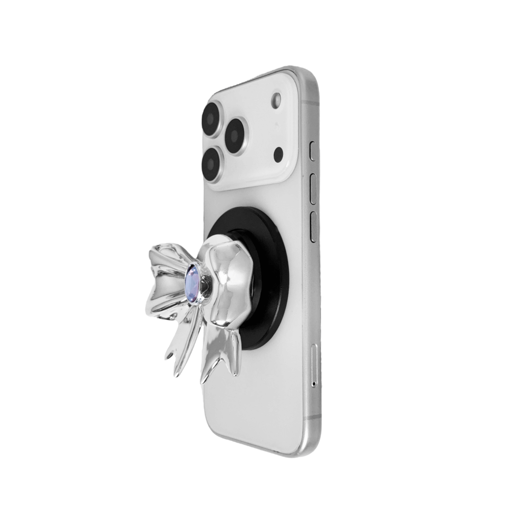 Gem Ribbon Phone Grip S available in silver, pink, black, and white ribbon designs, each featuring Swarovski crystal options: silver with pink, purple, white, blue, or black gems; pink with pink gem; black and white with black, white, or pink gems.