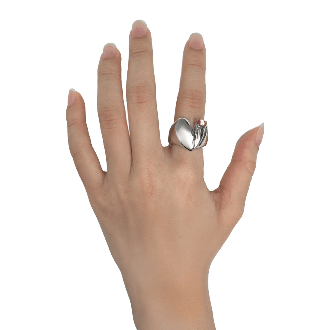 Wide band ring with a broken heart design and a pink Swarovski crystal centerpiece.