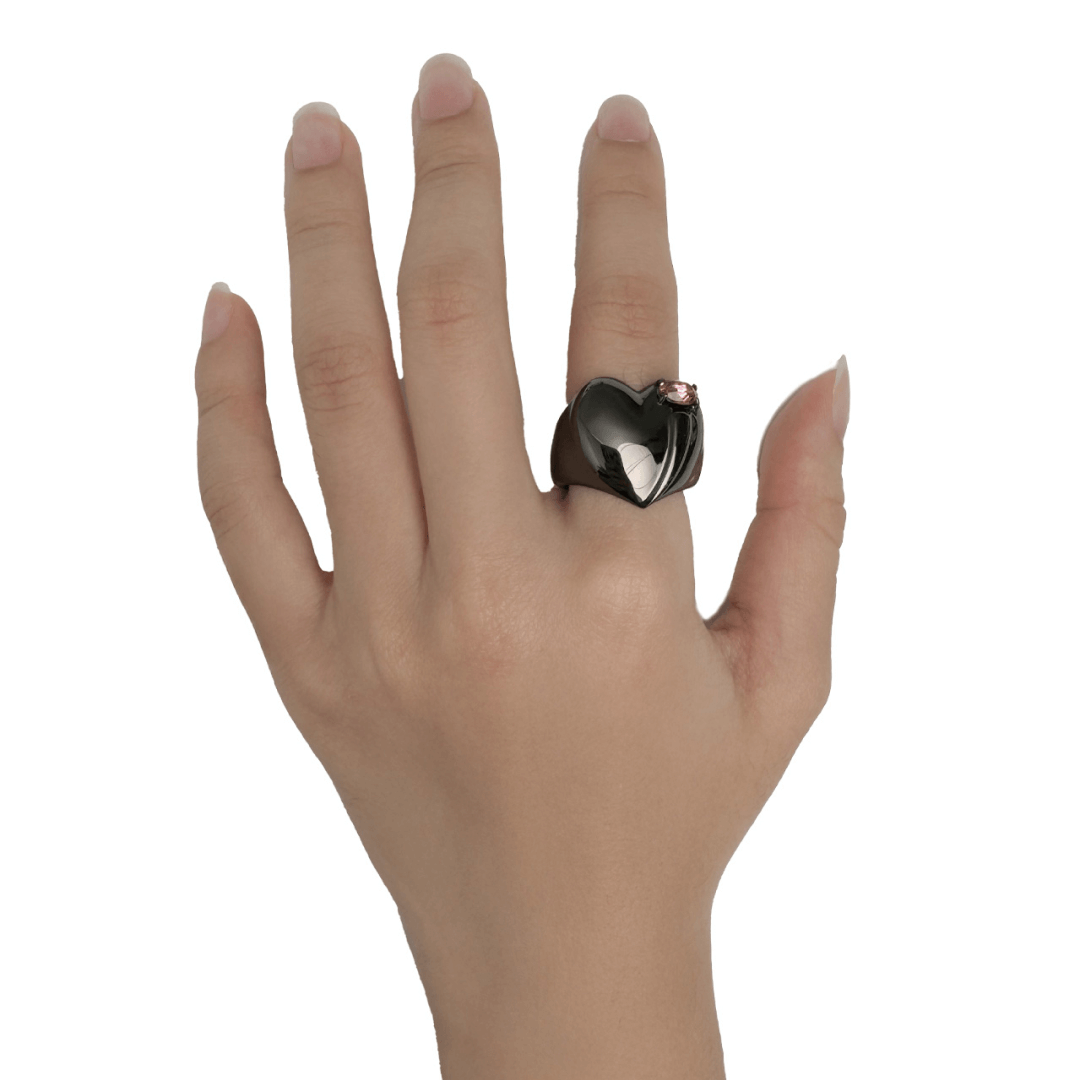 Wide band ring with a heart-shaped design and a pink Swarovski crystal centerpiece.