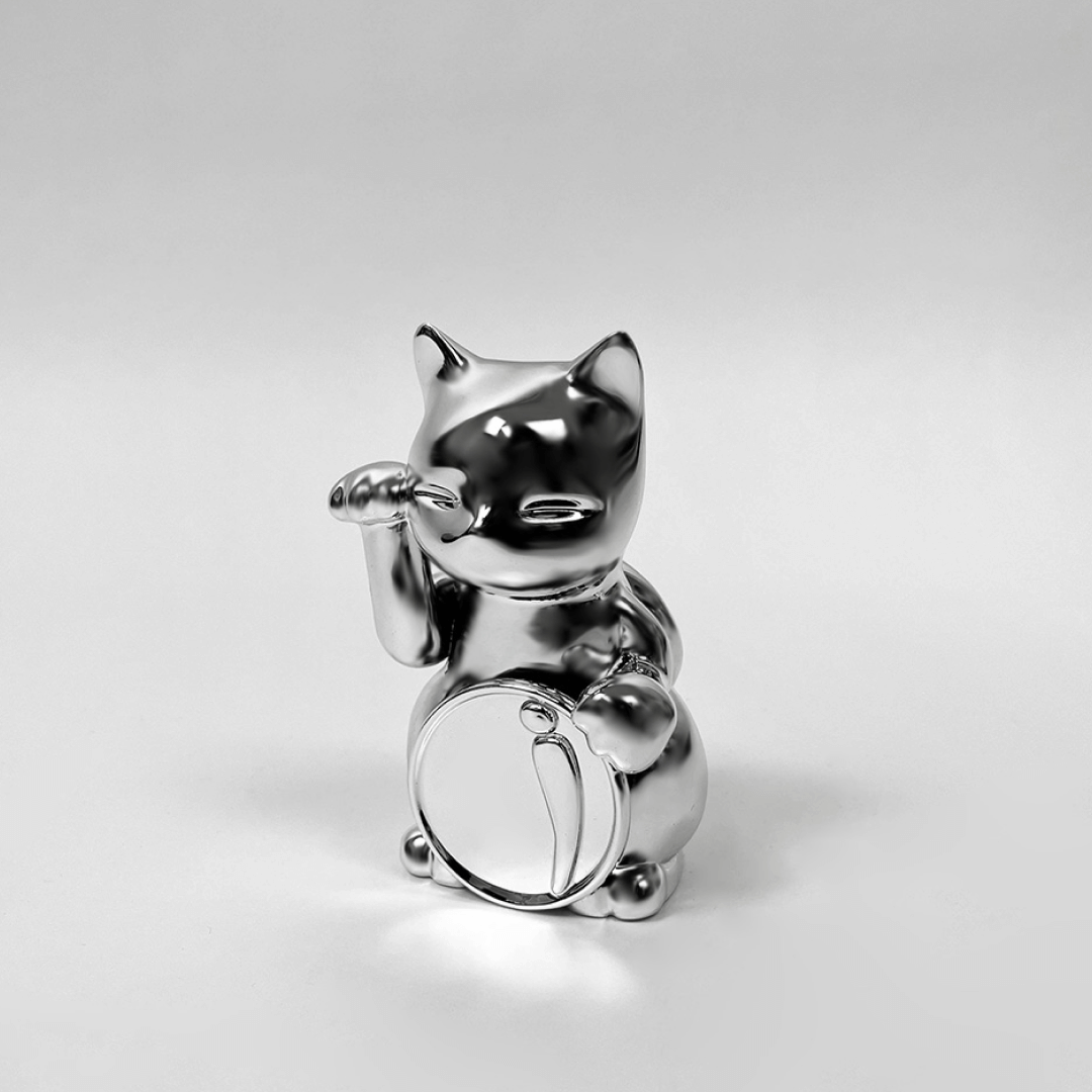 Futuristic chrome Maneki-neko sculpture – reflective silver lucky cat figure with raised paw and coin, blending traditional symbolism with modern minimalist form